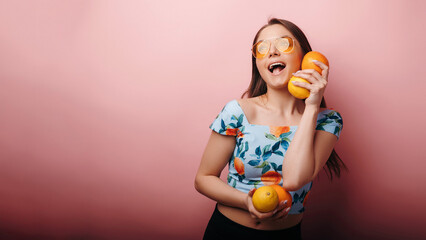 Smiling attractive girl holding oranges posing with funny expression