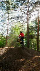 Fototapeta premium A enduro man jumps a dirt bike in a forest, from the back