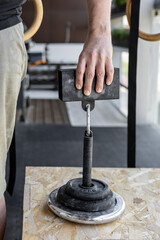 Close-up of a male hand gripping a metal pinch block grip during sport-specific exercise for...