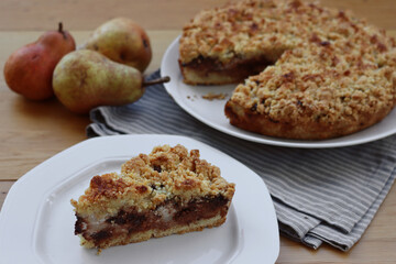 Traditional italian cake Sbrisolona cut in slices made with ricotta cheese, pear fruits and chocolate on a plate on wooden table
