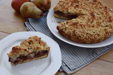 Traditional italian cake Sbrisolona cut in slices made with ricotta cheese, pear fruits and chocolate on a plate on wooden table