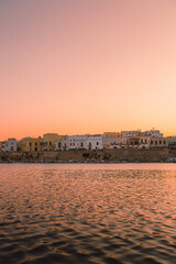 Gallipoli sandy beach at dusk with colorful sky and historic town in background