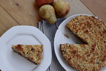 Traditional italian cake Sbrisolona cut in slices made with ricotta cheese, pear fruits and chocolate on a plate on wooden table