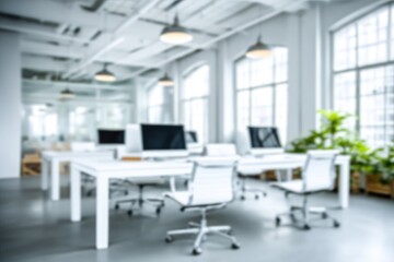 Softly blurred office interior with white desks, chairs, and computers under hanging lights, bathed in natural light from large windows