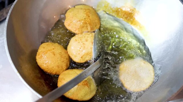 Indian bread or puri or pudi being fried in hot oil