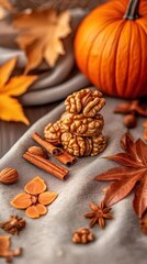 Fototapeta premium Walnuts stacked with cinnamon sticks, star anise and autumn leaves beside pumpkin on rustic fabric background, seasonal fall food concept