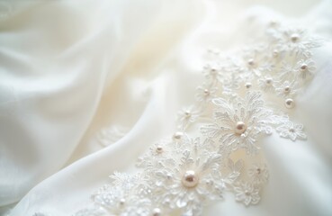 Fototapeta premium Close-up of white silk fabric with delicate lace embroidery, pearl accents, featuring airy folds, gentle curves. Luxurious bridal material offers elegant, clean texture perfect for wedding attire