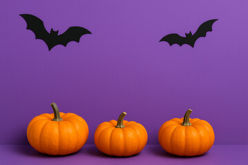 Minimalist Halloween Decor composition on a vibrant purple background with pumpkins and bats