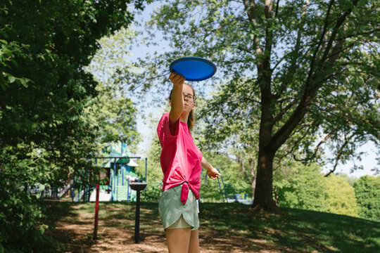 Girl prepares to throw disc in forest with trees and sunshine