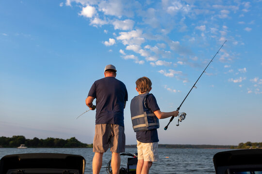 Father and son fishing together on a boat on a lake at sunrise