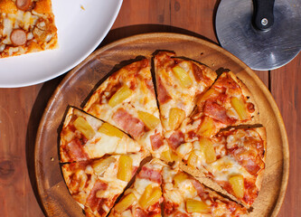 Top view pineapple and ham hawaiian pizza and chicken and sausage pizza on wooden plate, delicious melting cheese on wooden board, homemade cooking ingredients on dark background, food advertisement.
