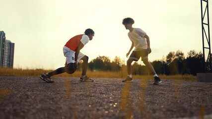 Cinematic handheld shot with two teens playing basketball on street, feet view. Sport and hobby for young people, do physical exercise and fitness for stay healthy and developing body conditions