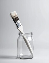 Paintbrush resting in a glass jar on a neutral backdrop