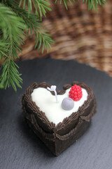 Beeswax candle designed as a slice of chocolate cake with raspberry topping. Handmade eco-friendly dessert candle for unique decor or thoughtful gifts.