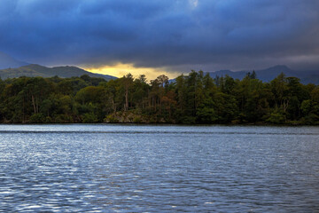 clouds above a lake, highlighted with the colours of a setting sun. Billowing clouds with warm colours of a setting sun above Lake Windermere