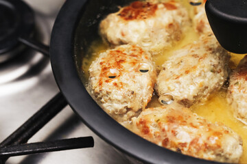 Frying minced meat cutlets under lid. Homemade traditional patties cooking in pan. Juicy golden kotlety mielone simmering in sauce. Classic Sunday dinner preparation. Comfort food fresh ground meat.
