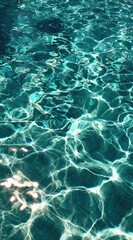 Fototapeta premium Shimmering, teal water with sun-dappled reflections dances across the surface. Light and shadows create an abstract, inviting texture that feels cool and serene
