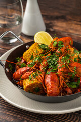 Cooked crayfish with corn and herbs in a serving pan