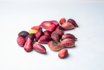 Close-up of fresh pink pistachio fruits on white background, scattered in a studio light setting