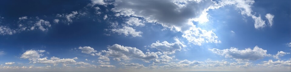 A wide view of a partly cloudy sky, with brilliant sunlight breaking through