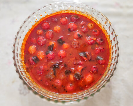 Indian coffee plum pickle made with Flacourtia jangomas fruits, also known as scramberry. A traditional South Indian recipe where red fruits are preserved with spices and oil.