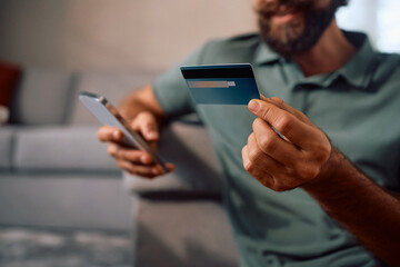 Close up of man using credit card for online payments at home.