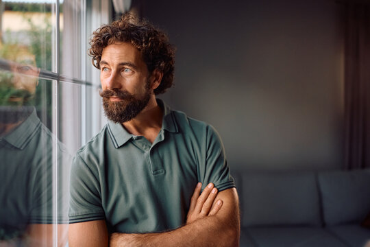 Pensive man looking through window at home.