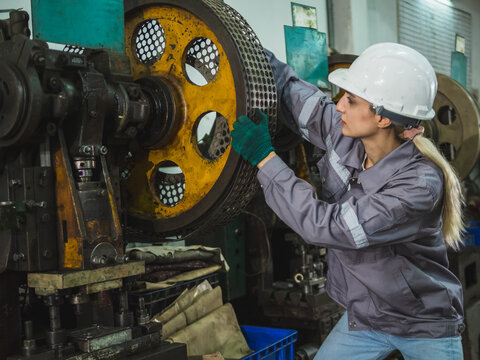 Industrial engineer technician professionl maintenance inspection quality control operating heavy machinery in manufacturing facility wearing safety gear and focusing on precision workplace safety.