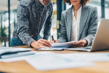 Professional reviewing mortgage options with clients, laptop and paperwork on desk.