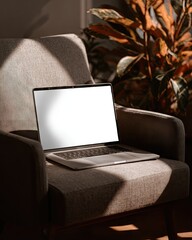 A laptop with a blank screen rests on a beige armchair, bathed in sunlight filtering through a nearby plant