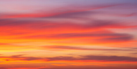 Obraz premium Colorful sky with clouds at sunset showing vibrant shades of orange and purple, creating a dramatic natural gradient with warm tones and a peaceful evening atmosphere.