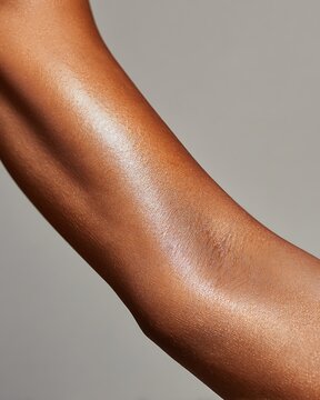 close-up of smooth hairless black woman forearm after waxing, glowing silky skin, minimal clean background, spa advertising