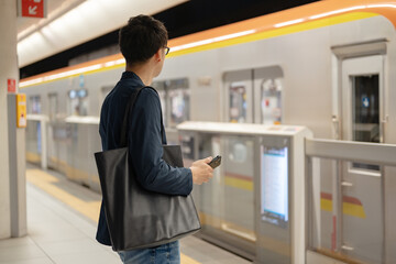 駅のホームで電車を待つ男性