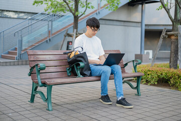 ベンチでパソコンを操作する男性