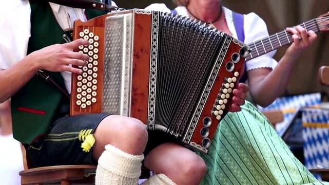 oktoberfest: Traditional Bavarian musicians playing accordion and guitar outdoors.