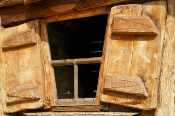 Wooden window with shutters in a rustic cabin during daylight showcasing craftsmanship and nature