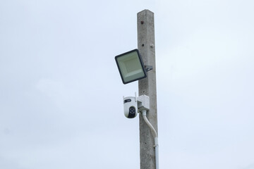 CCTV security camera on a pole with cloudy sky background, security concept
