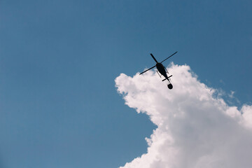 Silhouette of firefighter helicopter over clouds