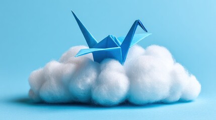 Origami crane rests peacefully atop a fluffy, cottony cloud against a soft blue backdrop, creating a serene and dreamlike miniature scene