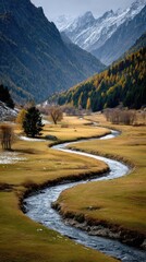 Winding river through autumnal valley, snow-capped peaks
