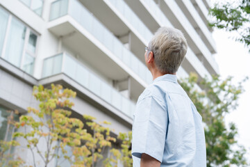マンションの前に立つシニア男性