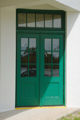 Green Double Doors of Classical old  Building Reflecting Greenery. Elegant painted doors with glass panes reflecting a serene outdoor environment, providing a sophisticated and timeless appearance, pe
