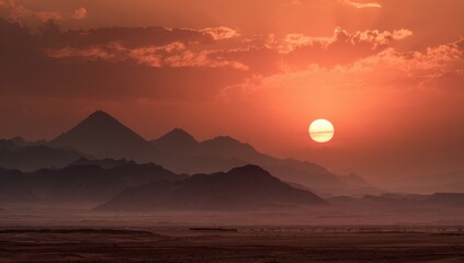 Desert mountain range at fiery sunset.  Vast, fiery sky with a  large, radiant sun, silhouetted mountains
