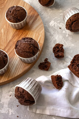 Delicious chocolate cupcakes on a wooden plate, concrete grey background. Poster for a pastry shop, bakery, cafe