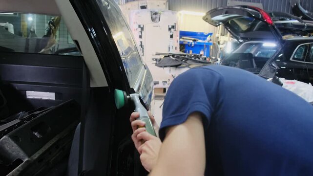 Specialist holds tool in hands polishing surface of vehicle. Man levels surface of car near door and carefully observes unevenness