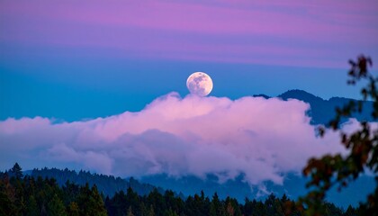 Full moon rising over a misty mountain range