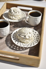 two cup of black coffee and two marshmallows on decorative white plates on marble surface tray