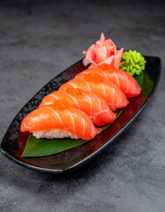 Fresh salmon nigiri served on a black plate