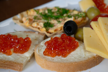 Sandwiches with red caviar, cheese and olives on a plate 