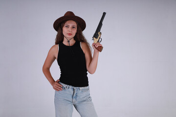 Young woman in hat holding vintage black powder revolver on gray background